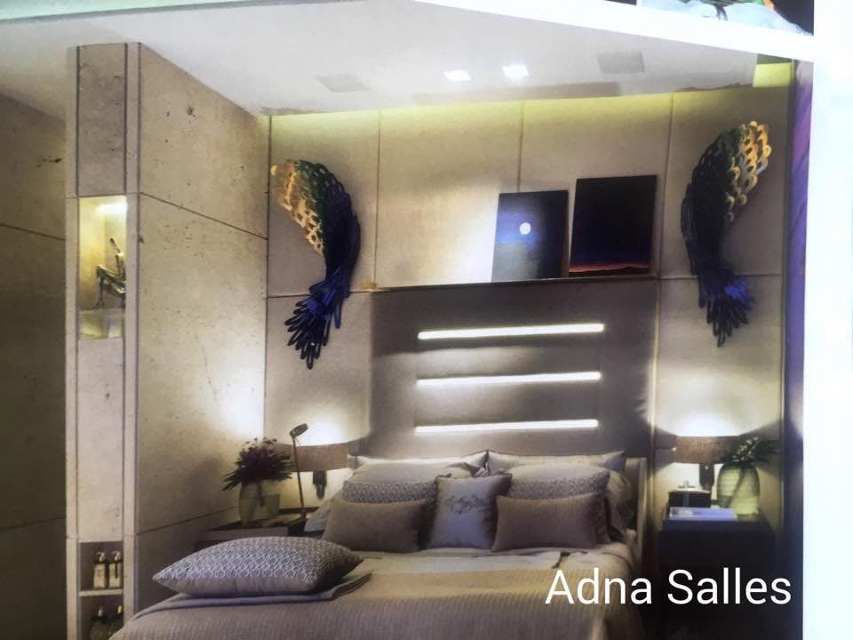 Quarto com duas esculturas de asas metálicas coloridas na parede, uma de cada lado da cabeceira iluminada