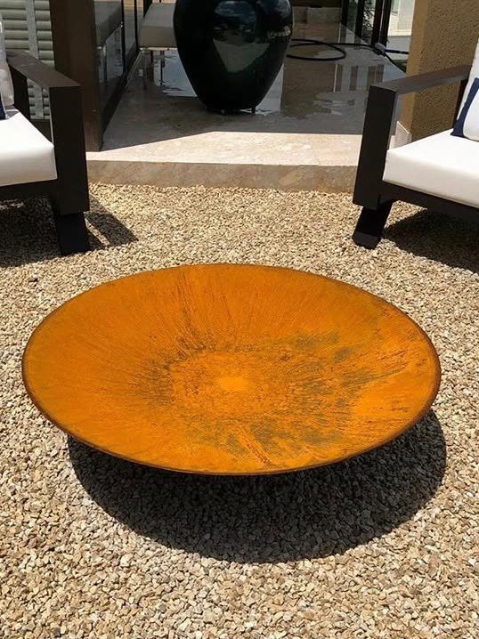Mesa de centro côncava em aço corten sobre cascalho, vista de cima