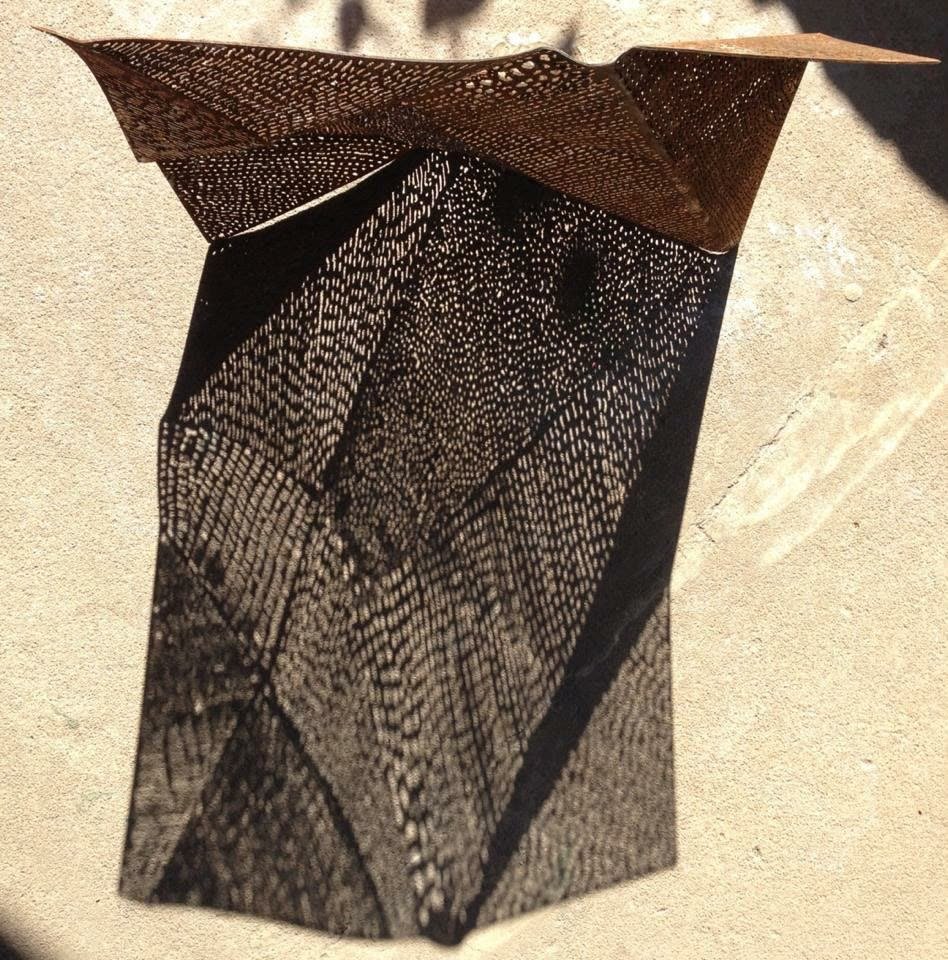 Peças Autorais 3 Escultura em chapa de aço corten perfurada e dobrada, com a sombra do padrão projetada no chão