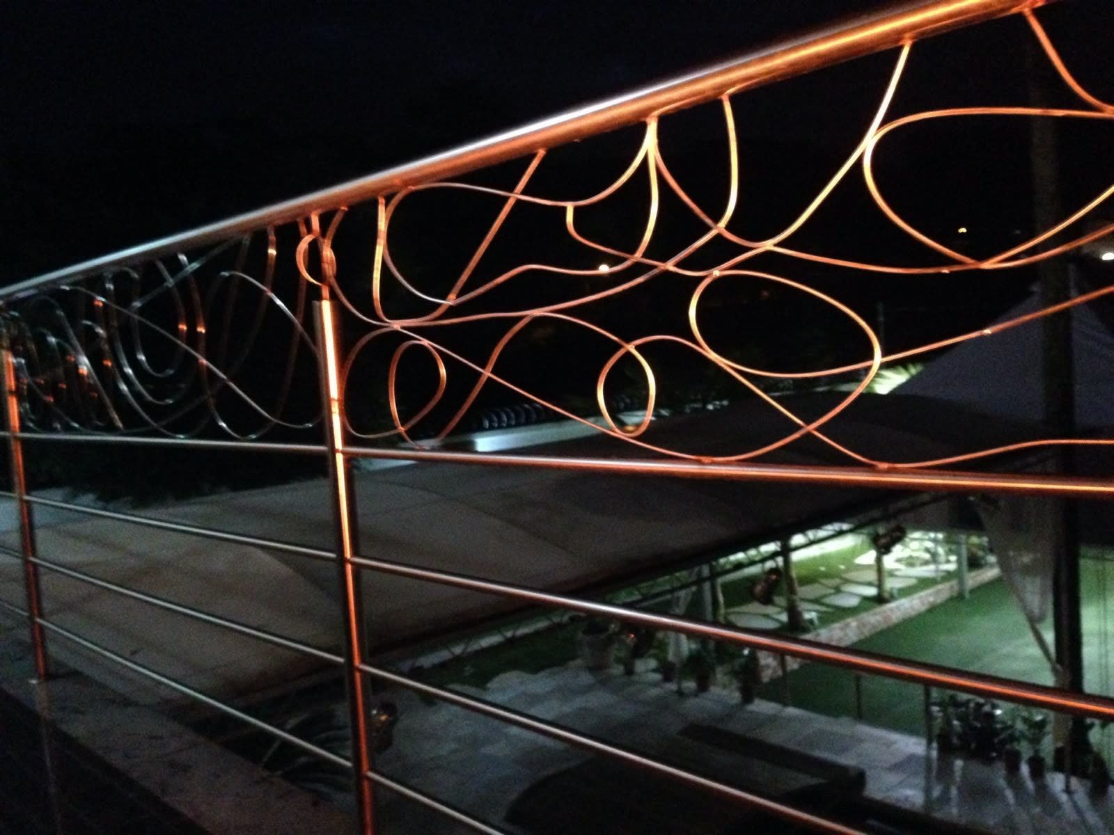 Guarda-corpo de varanda com desenho curvo orgânico, fotografado à noite