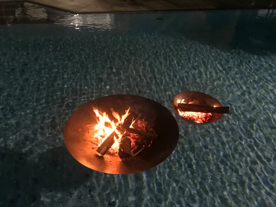 PROJETOS 8 Lareiras flutuantes duplas em aço corten acesas sobre a água da piscina, à noite