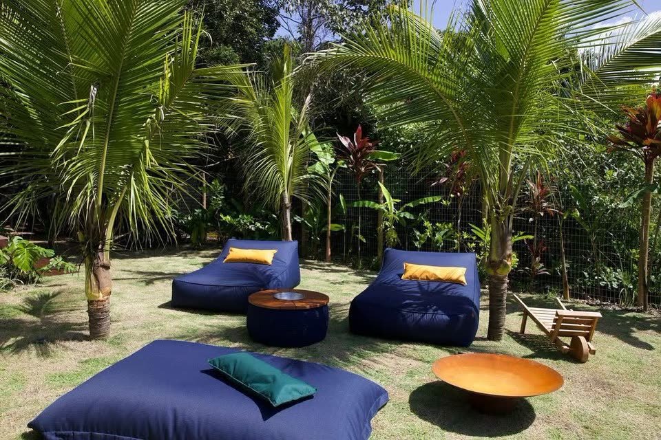 PROJETOS 20 Mesa de centro côncava em aço corten num jardim, entre puffs