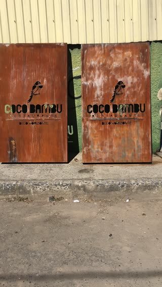 Duas placas em aço corten com a mesma logomarca vazada, apoiadas em um muro antes da instalação