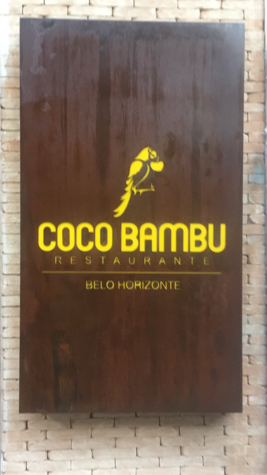 Painel de fachada em aço corten com logotipo aplicado, em parede de tijolos